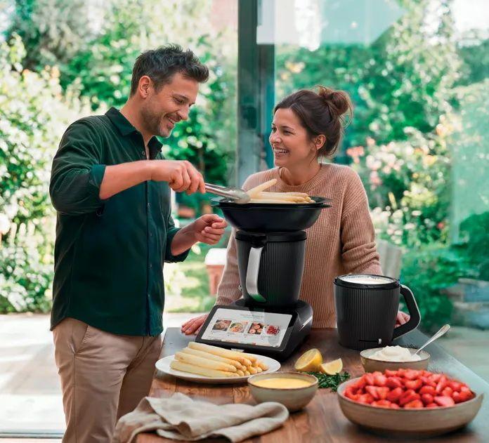 Ein Mann und eine Frau bereiten gemeinsam Spargel mit einem Küchenmixer zu